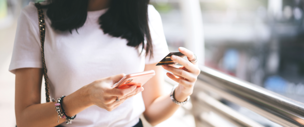 Woman holding a credit card and smartphone, representing financial transactions and credit risk.