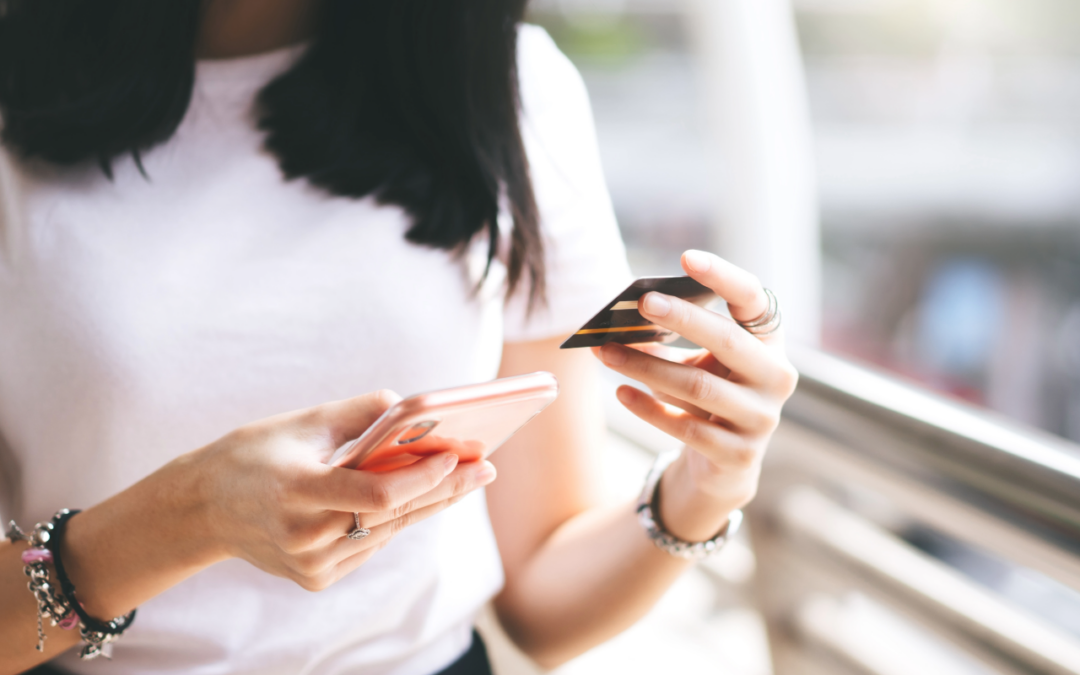 Woman holding a credit card and smartphone, representing financial transactions and credit risk.