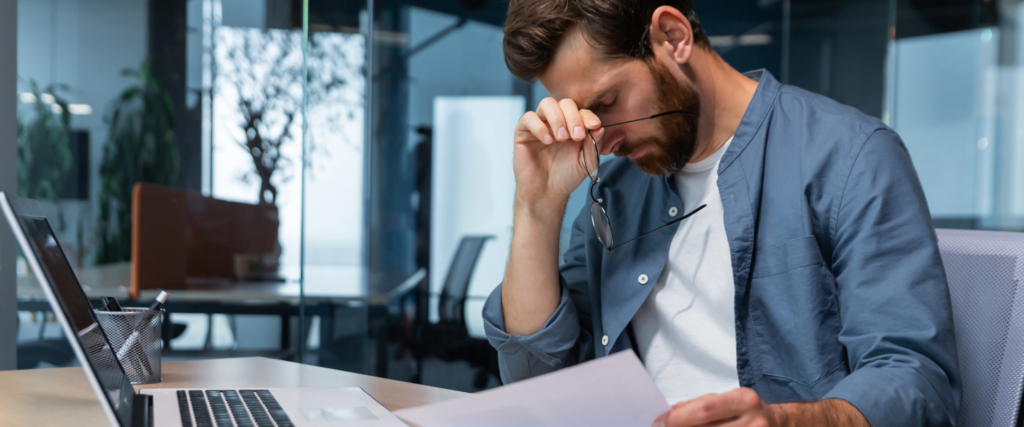 Man reviewing paperwork with a concerned expression, representing financial distress.